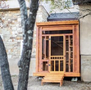 Wooden screened in enclosure with stairs and a door outside a building