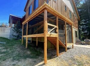 Wooden screened in cat enclosure structure on the outside of a home along the foundation