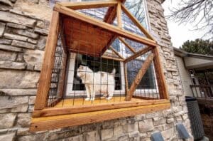 Wooden screened in box enclosure fixed on the outside of a window to create a catio